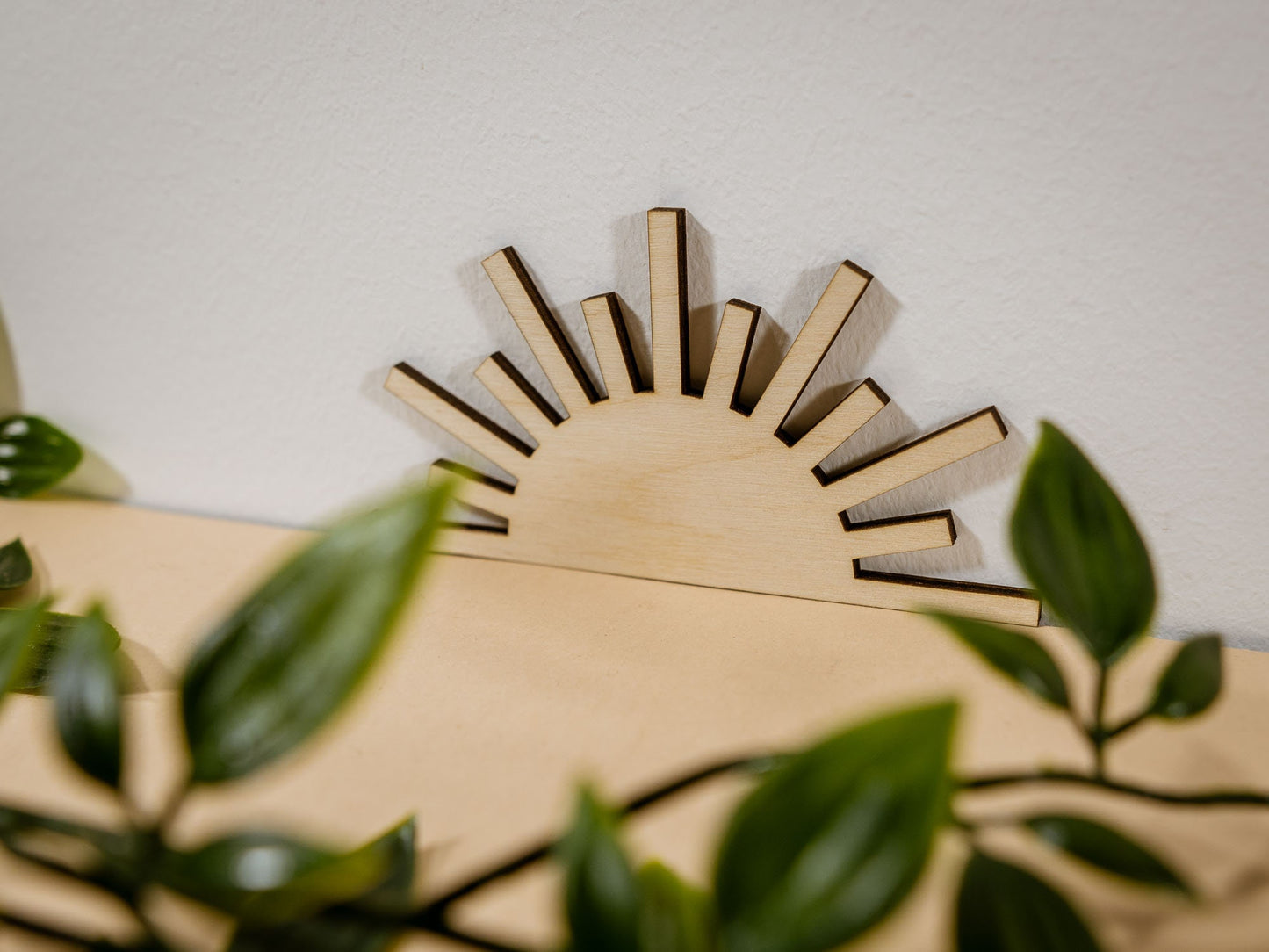 Wooden sun-shaped decor item on a beige surface with lace and leaves.