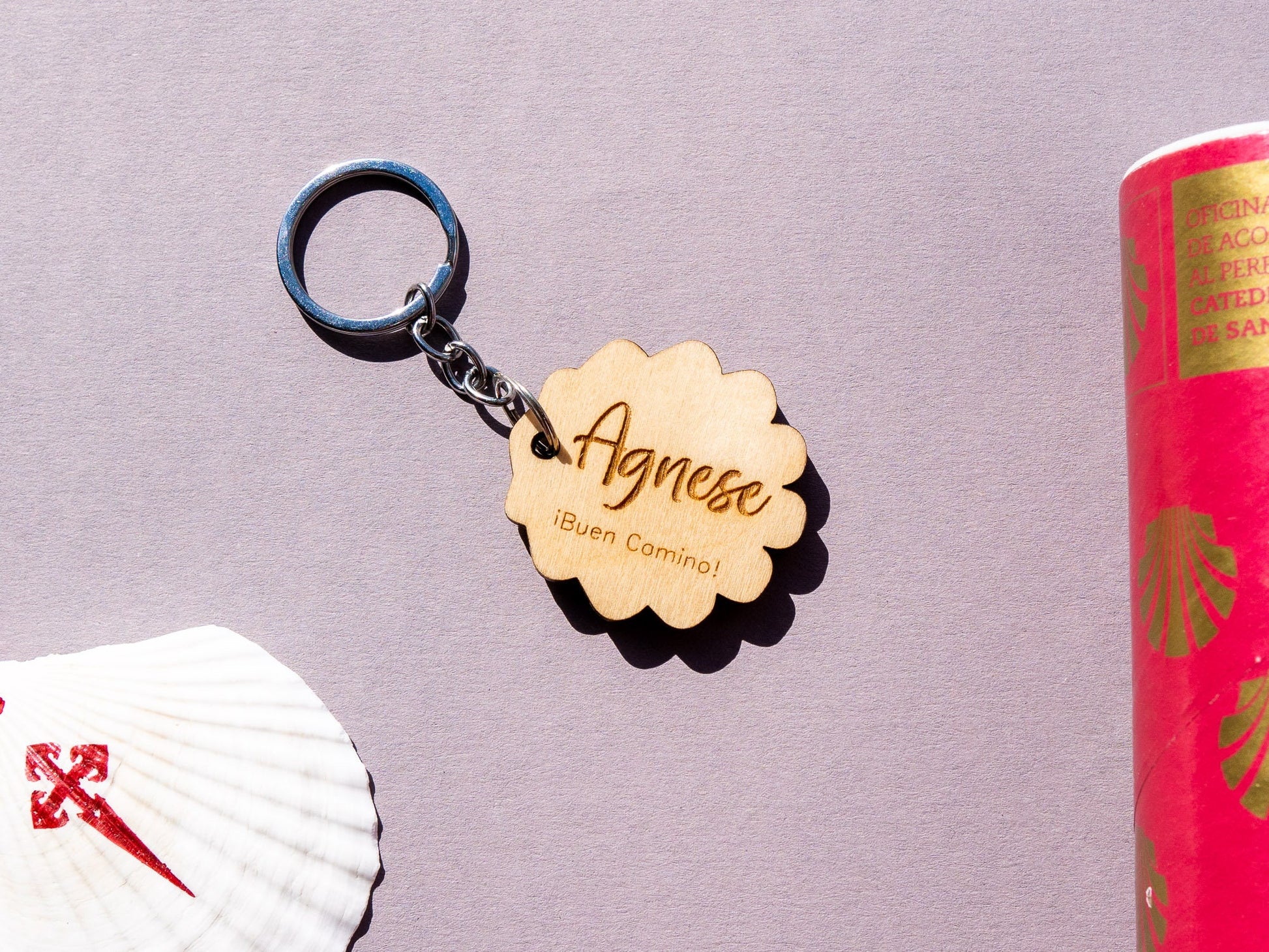 Keychain with a wooden tag labeled 'Agnese' on a purple background with a book and shell.