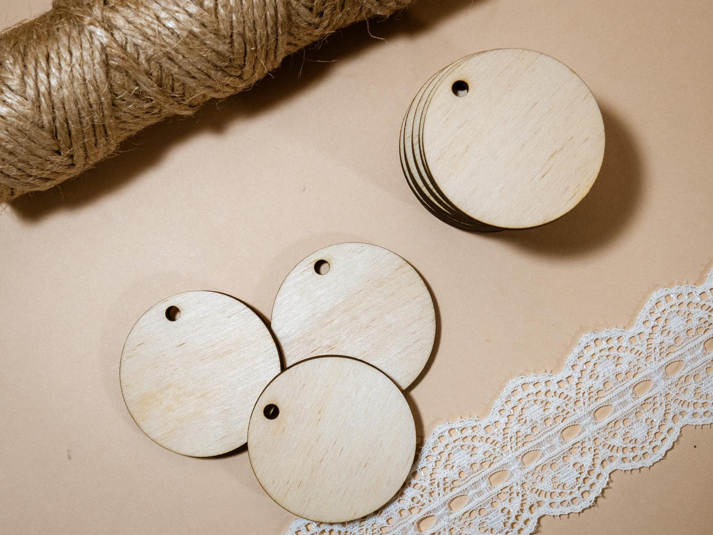 Wooden tags with holes on a beige surface with lace and twine.