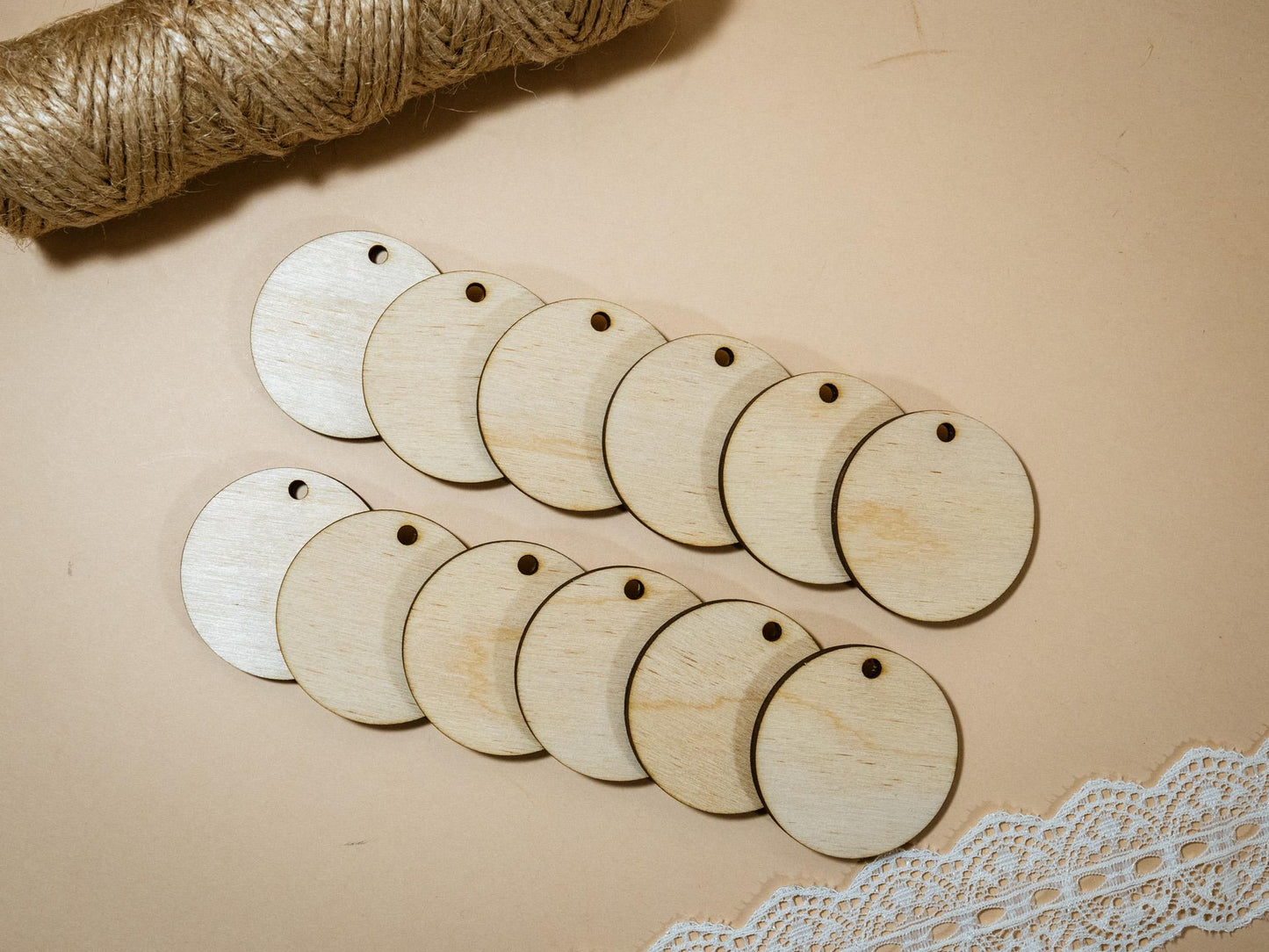 Wooden tags with holes on a beige surface with lace and twine.