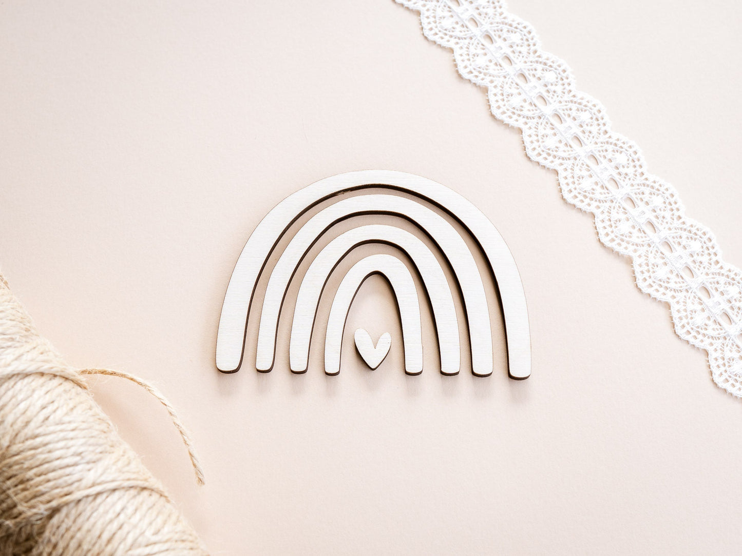 Wooden rainbow decoration with a heart on a light pink background
