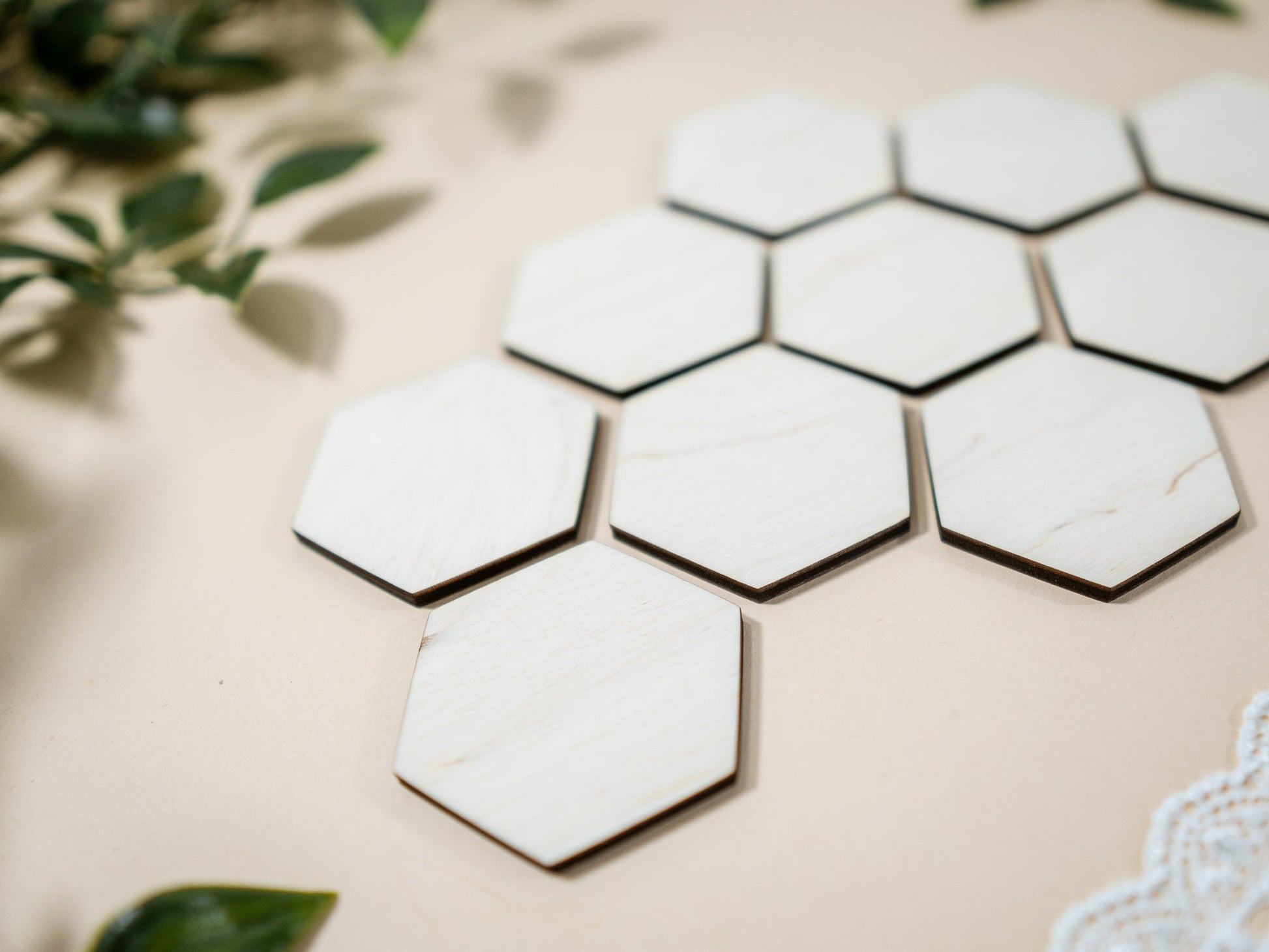 Hexagonal marble tiles on a beige background with green leaves.