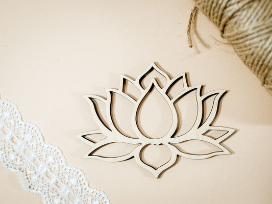 Wooden lotus flower decoration on a beige background with lace and straw elements.