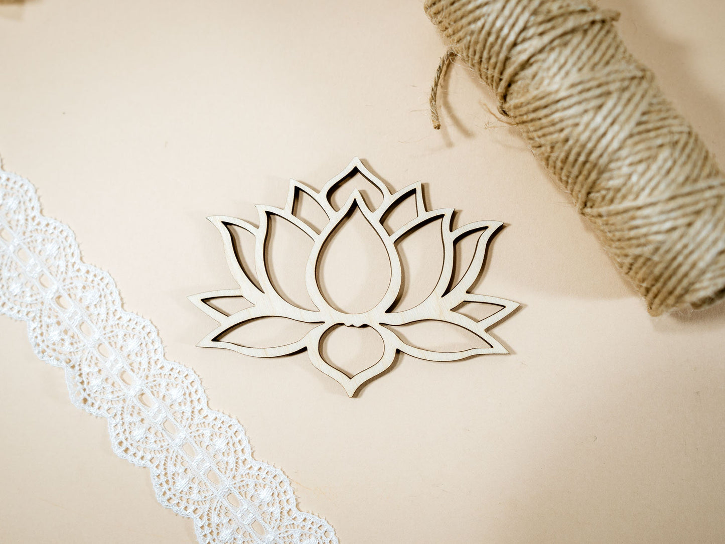 Wooden lotus flower decoration on a beige surface with lace and twine.
