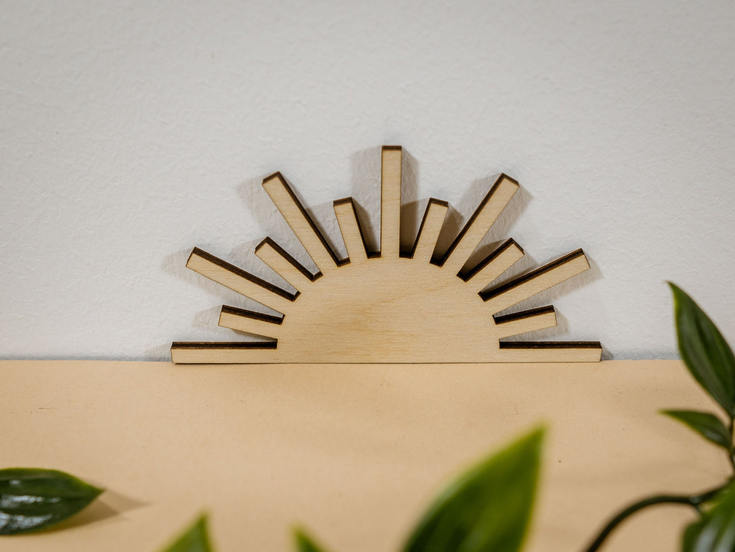 Wooden sun-shaped decor item on a beige surface with lace and leaves.