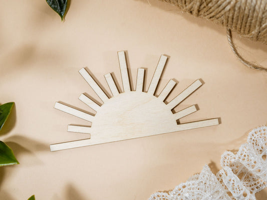 Wooden sun-shaped decor item on a beige surface with lace and leaves.