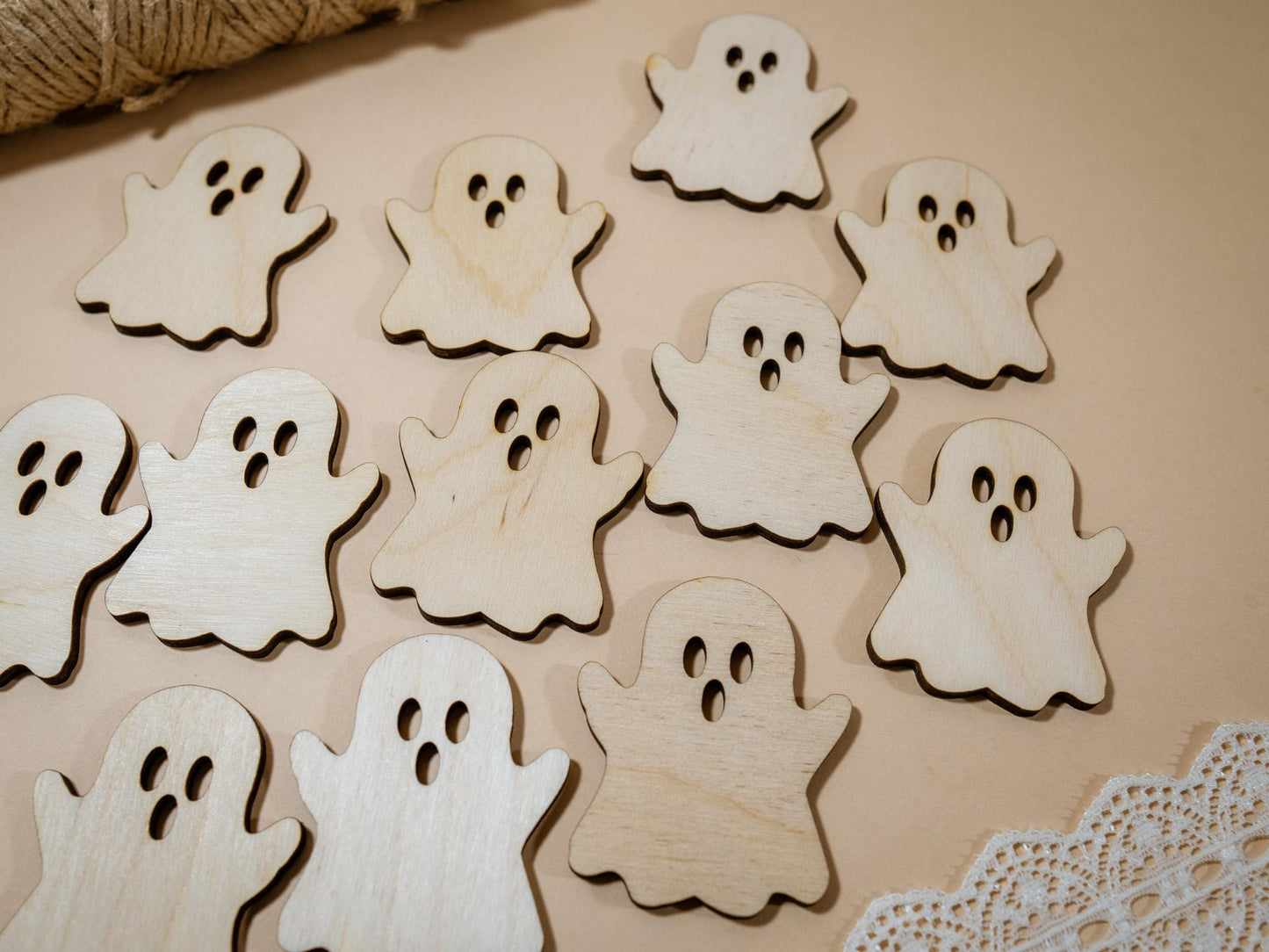 Wooden ghost cutouts on a beige surface with lace trim