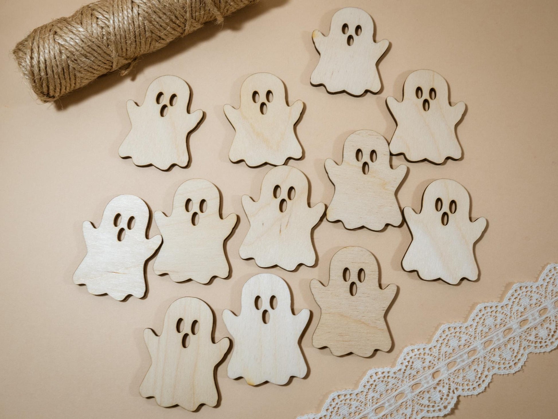 Wooden ghost shapes on a beige surface with twine and lace trim.