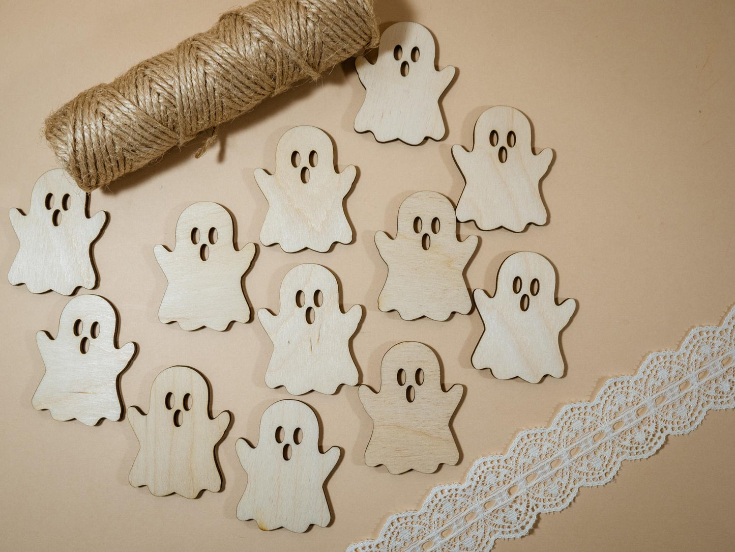 Wooden ghost cutouts on a beige background with twine and lace trim.