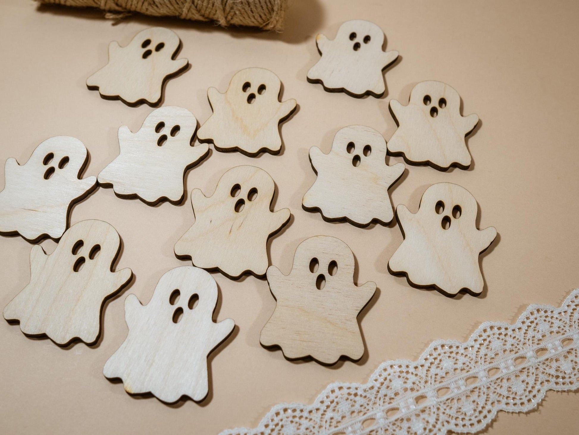 Wooden ghost shapes on a beige surface with twine and lace trim.