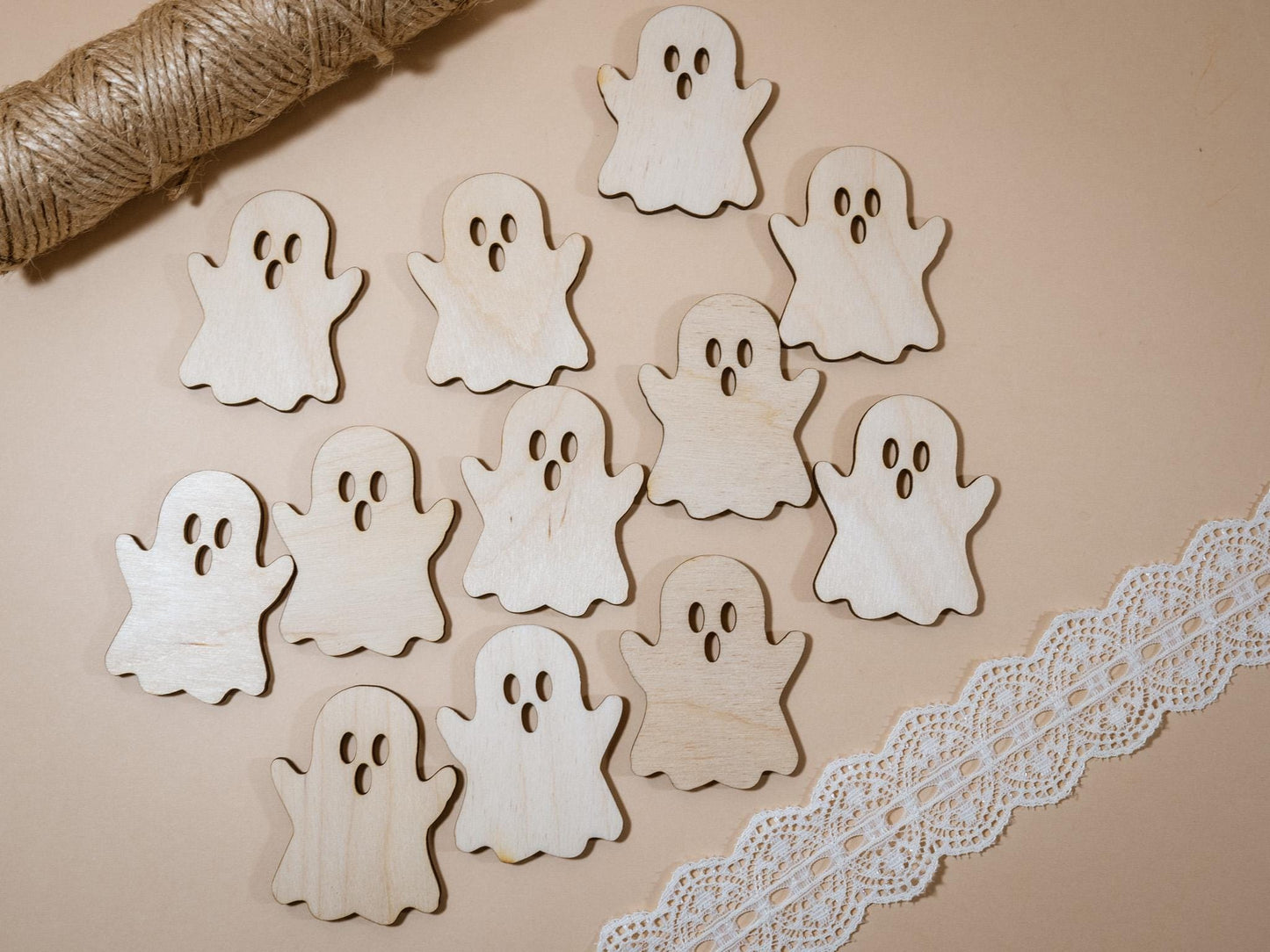Wooden ghost shapes on a beige surface with twine and lace trim.