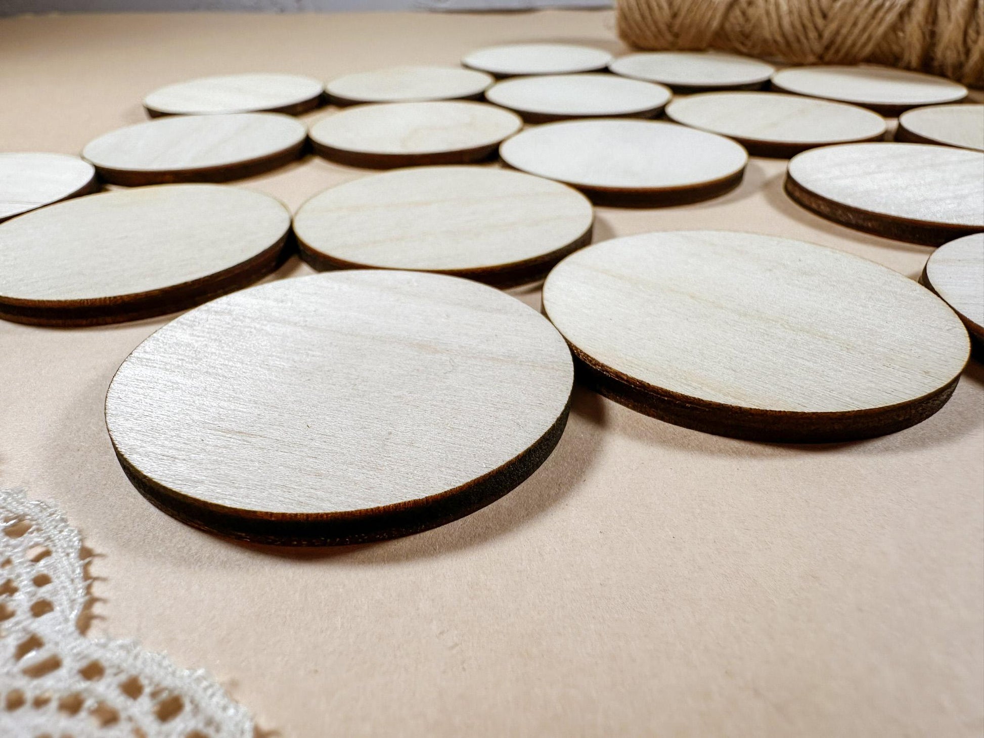 Round wooden coasters on a beige surface with lace and twine.