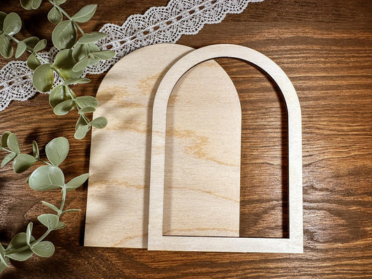 Two wooden arches on a wooden surface with eucalyptus leaves and lace.