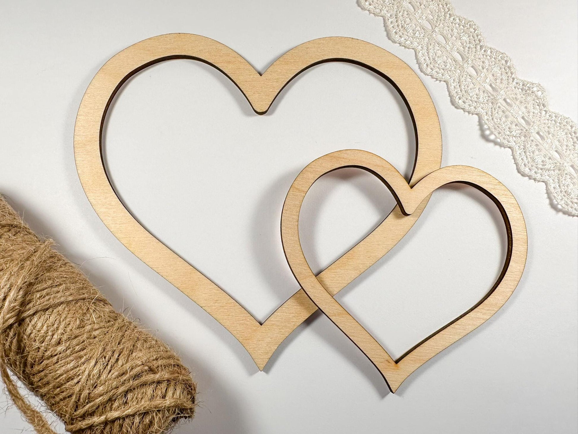 Two wooden heart shapes with twine on a light background