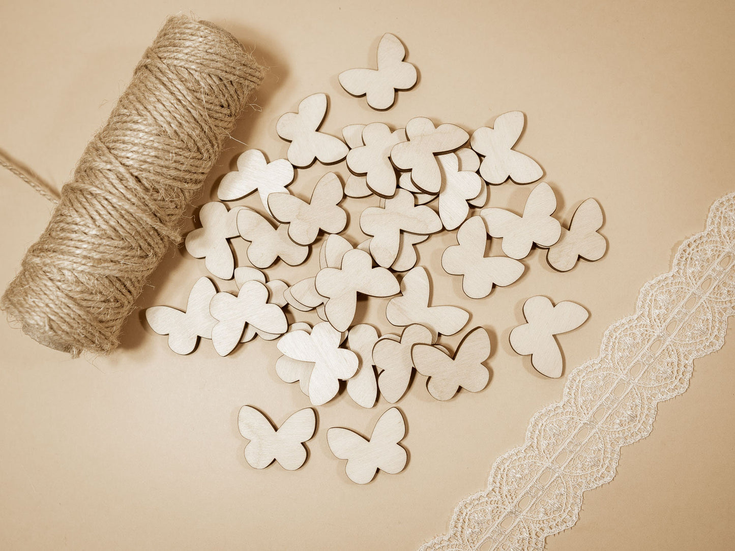 Wooden butterfly shapes on a beige surface with lace and yarn.