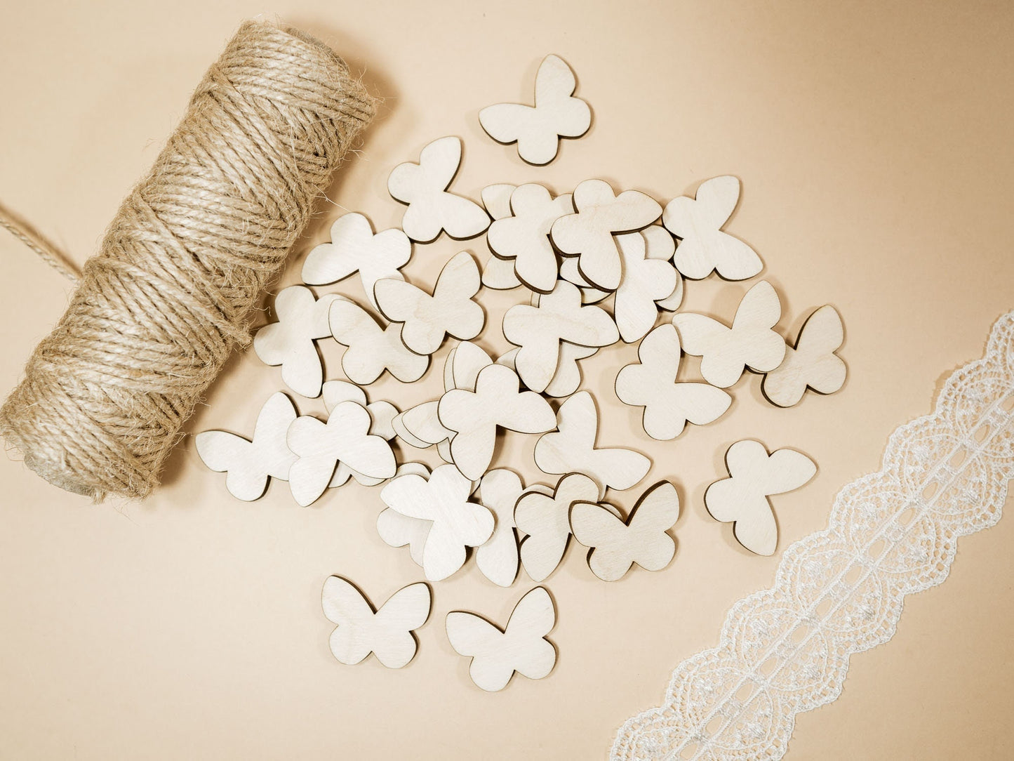 Wooden butterfly decorations with twine and lace on a beige background