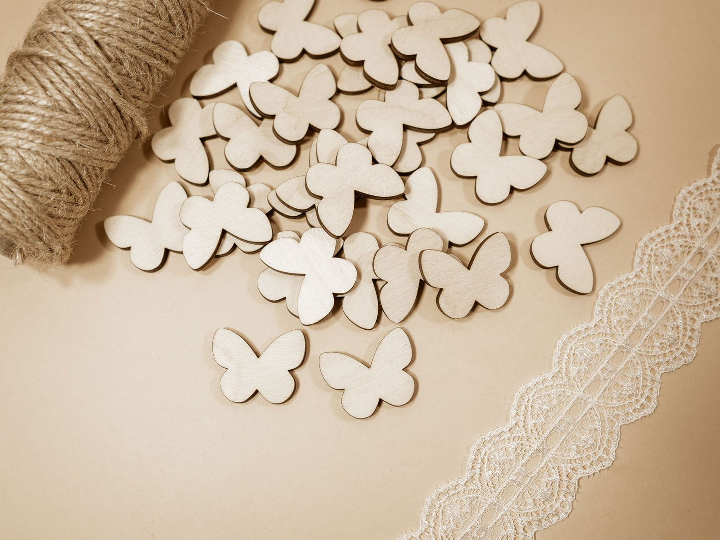 Wooden butterfly shapes on a beige surface with lace and yarn.