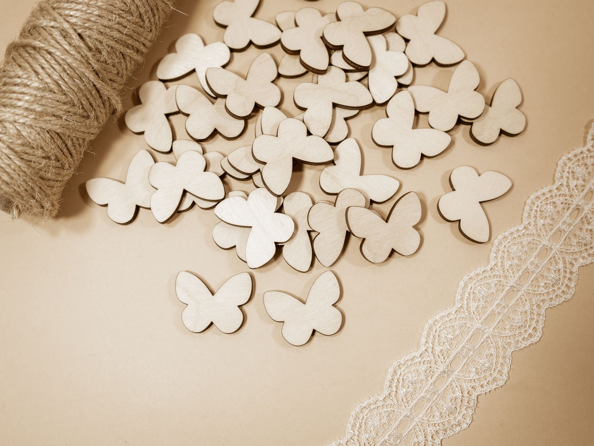 Wooden butterfly shapes on a beige surface with lace and yarn.