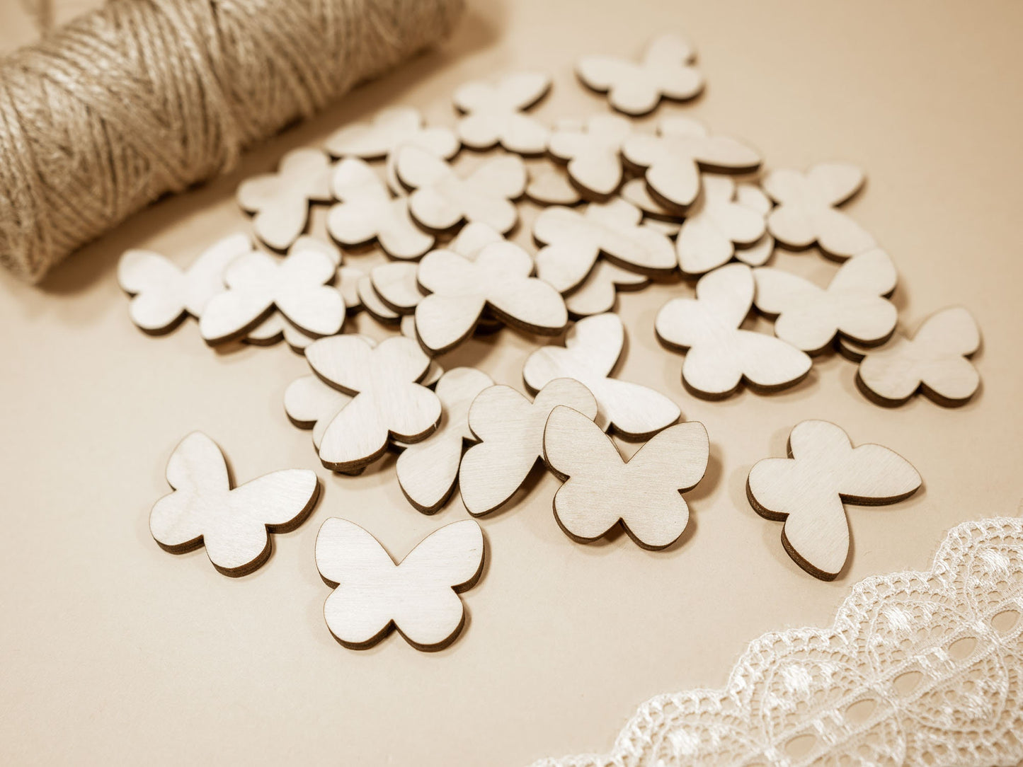 Wooden butterfly shapes on a beige surface with lace and yarn.