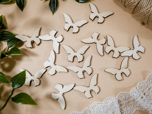White butterfly decorations on a beige surface with green leaves and lace fabric.